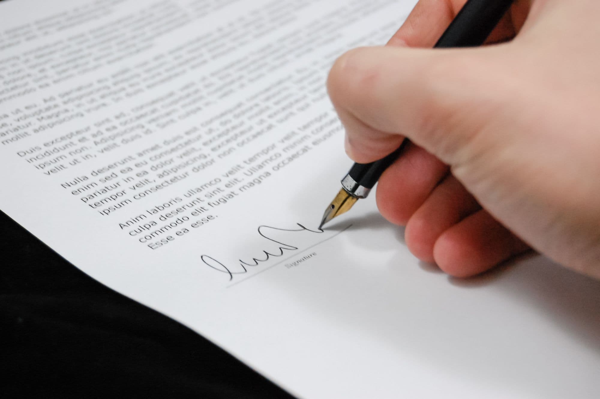 Hand die met een vulpen een officieel document ondertekent