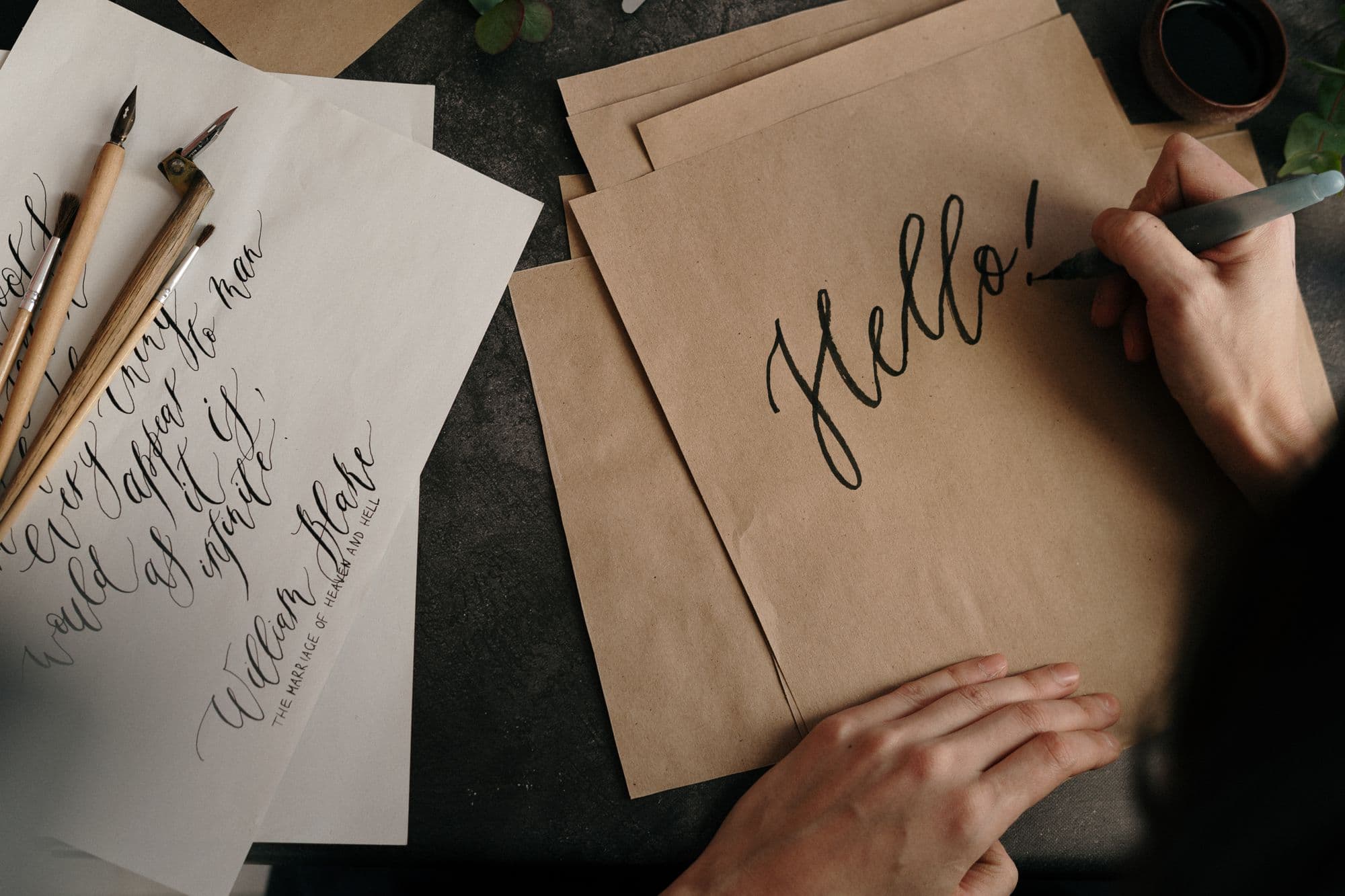 Iemand schrijft 'Hello!' in sierletters op kraftpapier